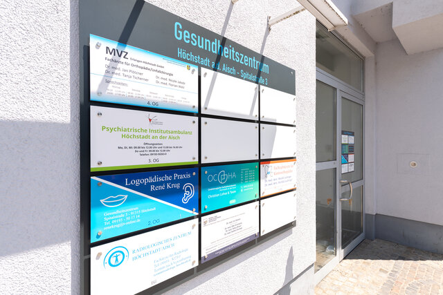 Außenansicht des Gebäudes mit Ärztetafel und Eingangstür