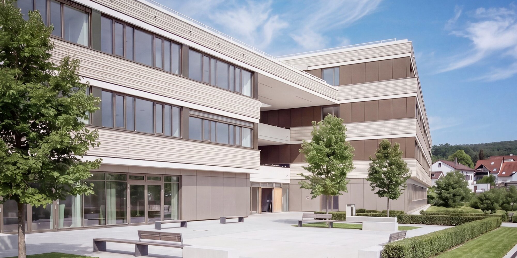 Außenansicht der Psychosomatischen Fachklinik Altmühltal, modernes, mehrstöckiges Gebäude mit schattenspendenden Bäumen und Grünanlage