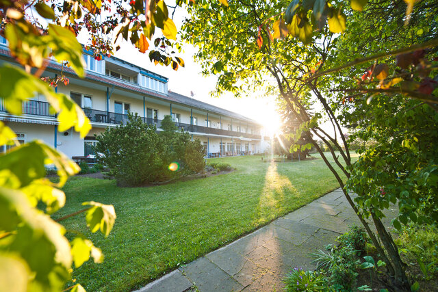 Außenansicht Soziotherapeutisches Wohnheim Eggenhof, zweistöckiges Gebäude im Grünen gelegen, bei Sonnenuntergang
