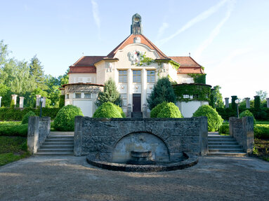 Außenansicht Festsaal, ein Gebäude im Jugendstil, mit Treppenanlage und kleinem Park auf dem Gelände des Bezirksklinikums Ansbach