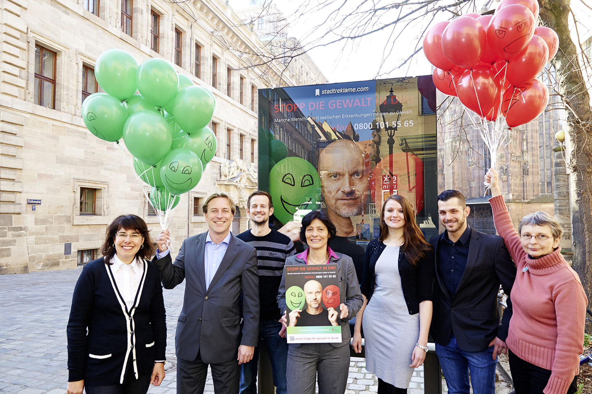 Gruppenbild der Mitarbeitenden der Präventionsambulanz Nürnberg vor einem Plakat der Kampagne "Stopp die Gewalt ind dir"