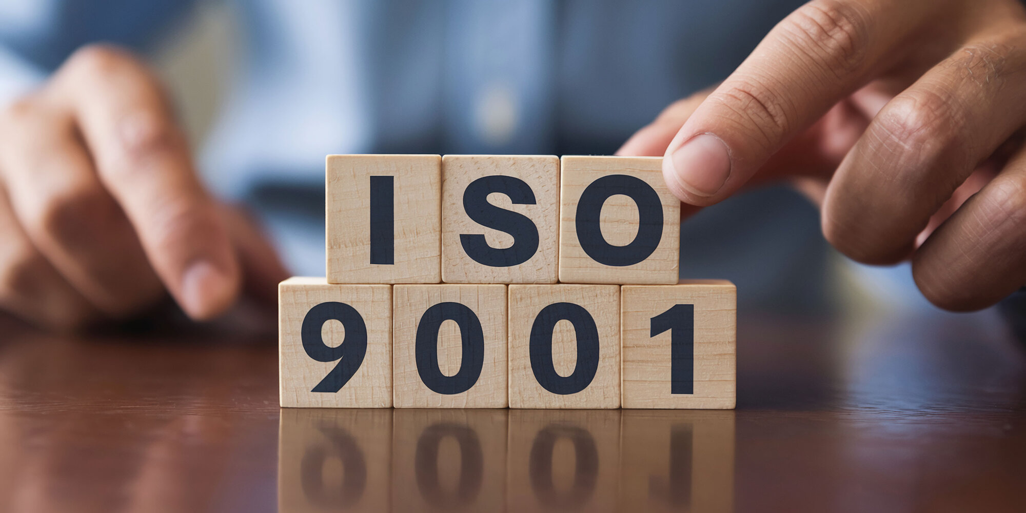 Symbolbild, gestapelte Holzwürfel mit der Aufschrift ISO 9001