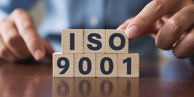 Symbolbild, gestapelte Holzwürfel mit der Aufschrift ISO 9001